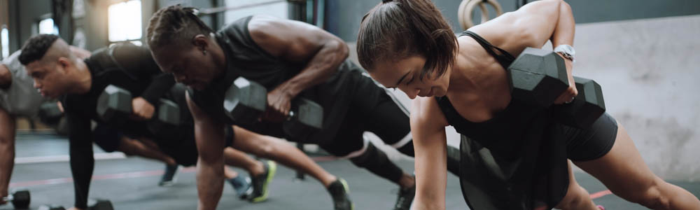 Men and women in a group fitness dumbbell row workout in a class Men and women in a group fitness dumbbell row workout in a class